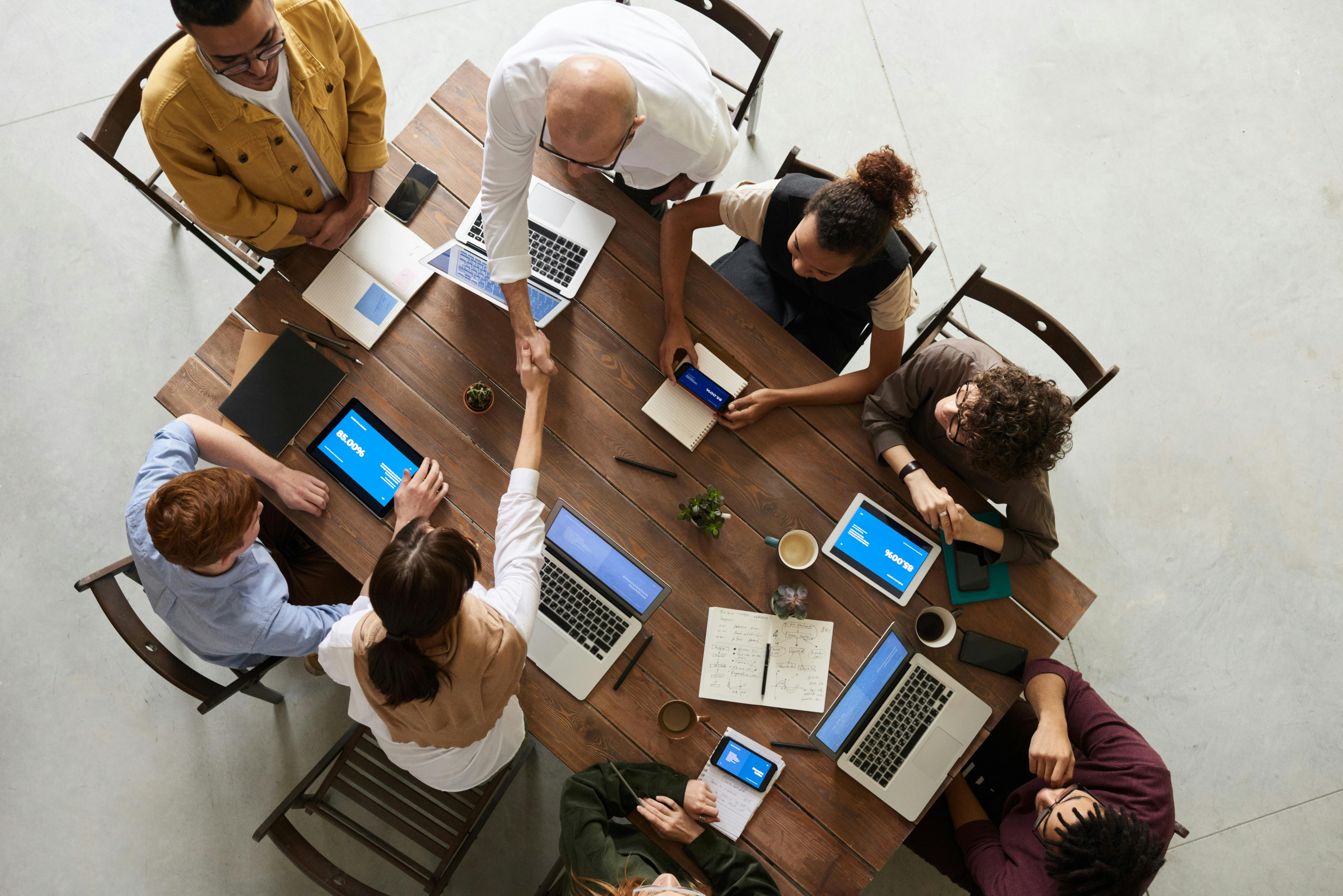 Team meeting with laptops and documents on wooden table